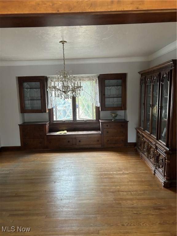 unfurnished dining area with light wood-type flooring, crown molding, and a chandelier