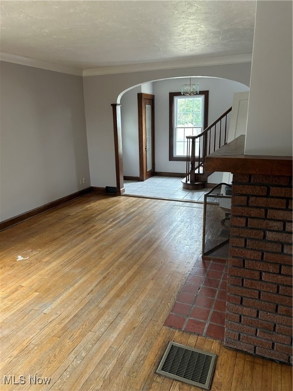 living room with light hardwood / wood-style flooring, ornamental molding, a textured ceiling, and an inviting chandelier