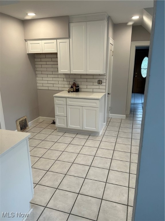 kitchen with white cabinets, light tile patterned flooring, and decorative backsplash