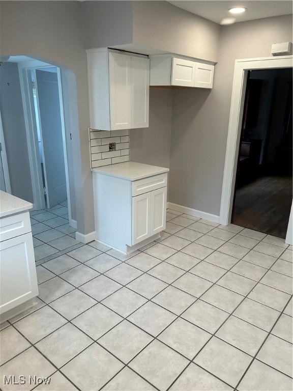 kitchen featuring light tile patterned floors, decorative backsplash, and white cabinetry