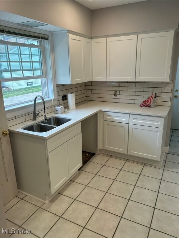 kitchen with light tile patterned floors, white cabinets, backsplash, and sink