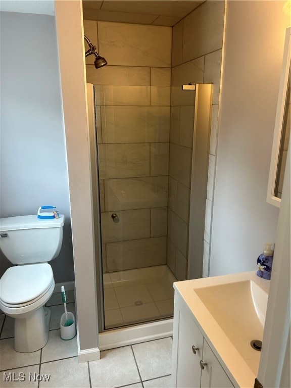 bathroom with tile patterned flooring, a shower with door, toilet, and vanity