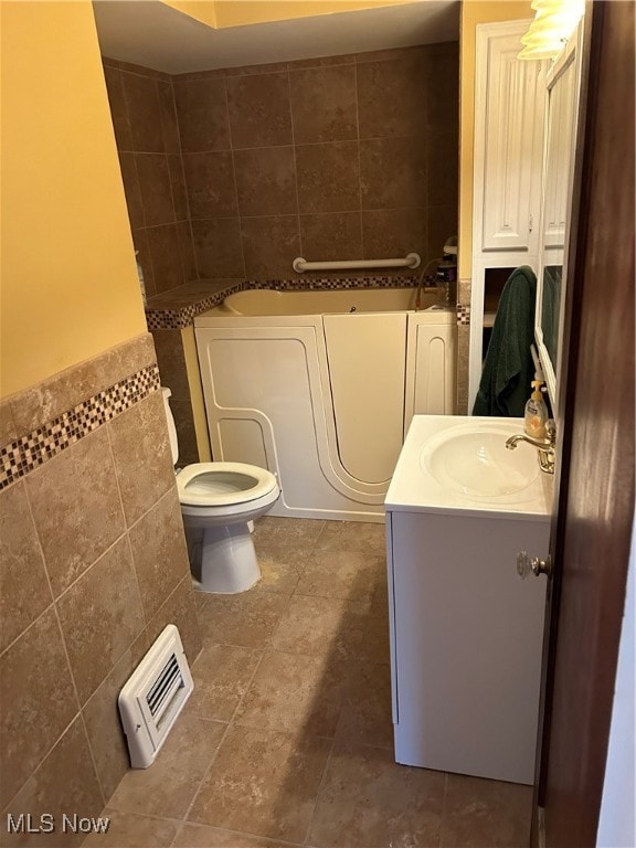 bathroom featuring vanity, tile walls, a bathtub, and toilet