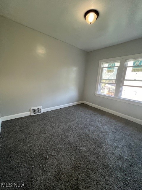 unfurnished room featuring dark colored carpet