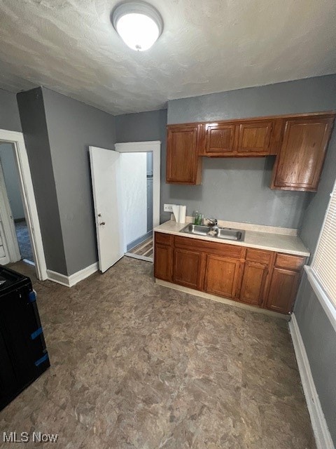 kitchen with a textured ceiling, black range with electric cooktop, and sink