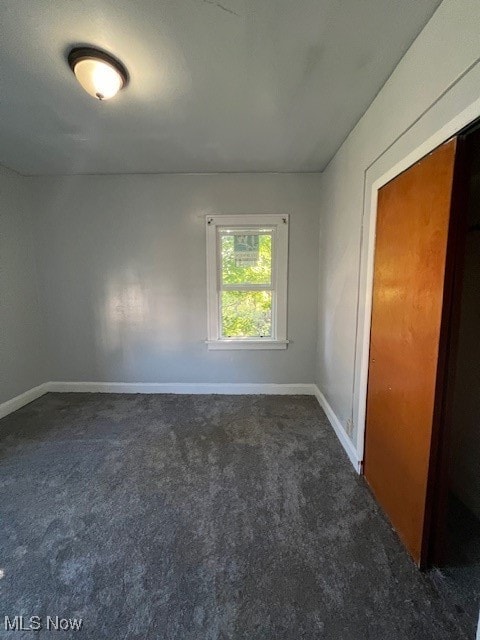 spare room featuring dark colored carpet