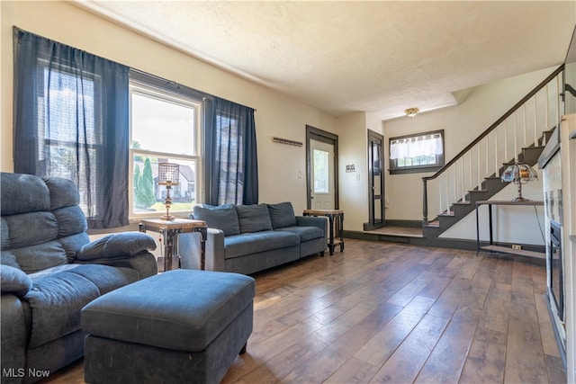 living room with a textured ceiling, plenty of natural light, and dark wood-type flooring