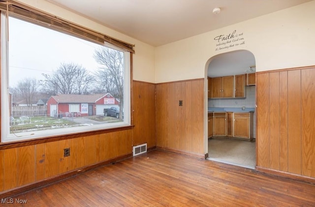 spare room featuring wood walls and wood-type flooring