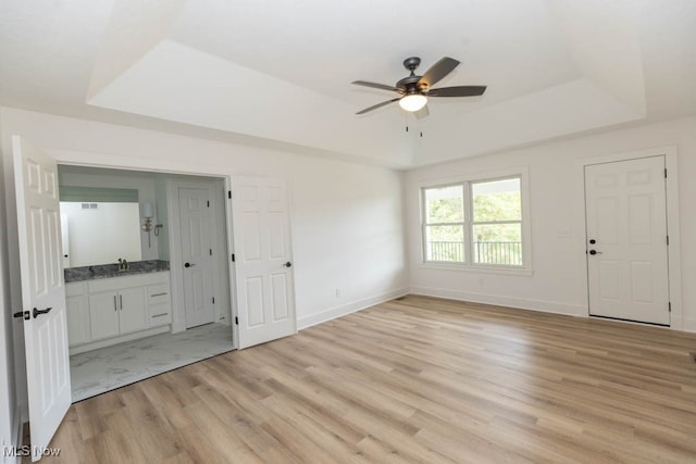 interior space featuring light hardwood / wood-style flooring, ceiling fan, a raised ceiling, and sink