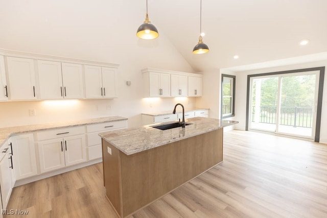 kitchen featuring light wood-type flooring, white cabinetry, sink, and an island with sink