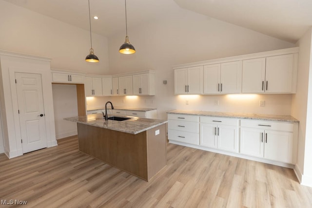 kitchen with a center island with sink, sink, high vaulted ceiling, and white cabinetry