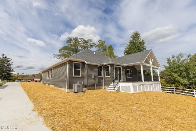 back of house with central air condition unit and a yard