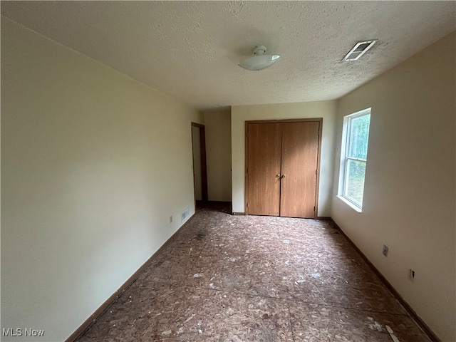 unfurnished bedroom featuring a textured ceiling and a closet