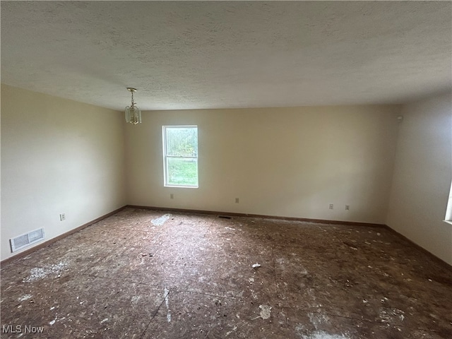 empty room with a textured ceiling and a notable chandelier