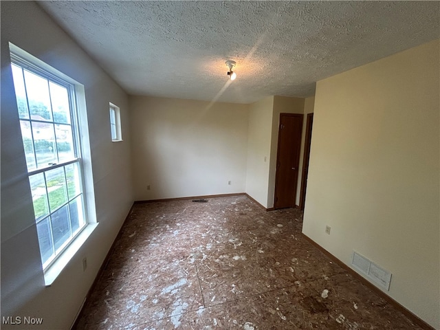 unfurnished room featuring a textured ceiling