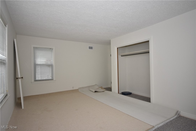 unfurnished bedroom featuring a closet, carpet floors, and a textured ceiling