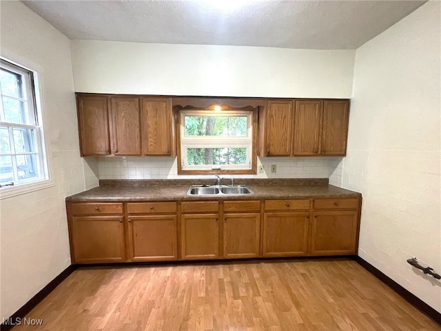 kitchen featuring light hardwood / wood-style flooring, decorative backsplash, a textured ceiling, and sink