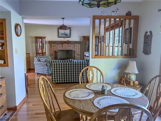 dining space with light hardwood / wood-style flooring and a brick fireplace