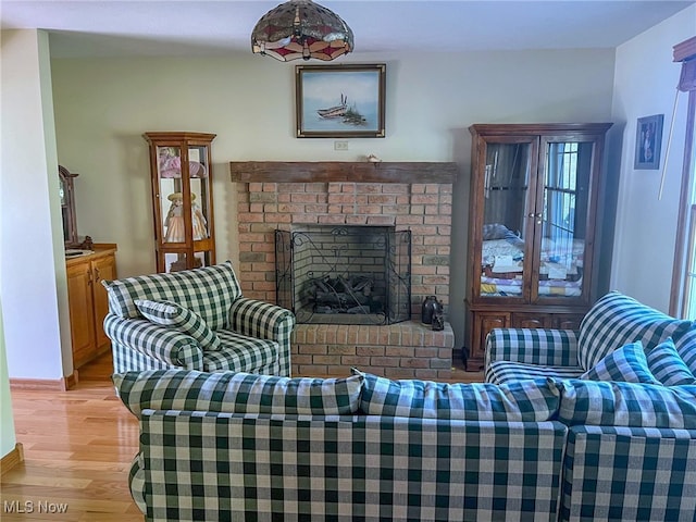 living room with a brick fireplace and light hardwood / wood-style floors