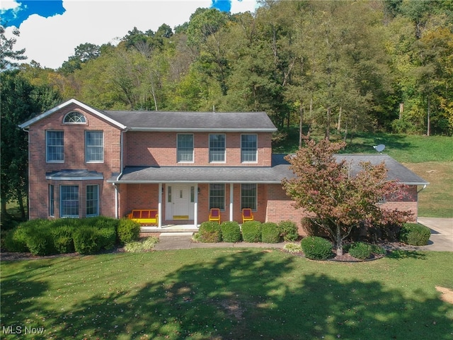 colonial house with covered porch and a front yard