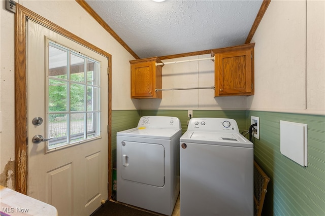 washroom with ornamental molding, cabinets, washer and dryer, and a textured ceiling