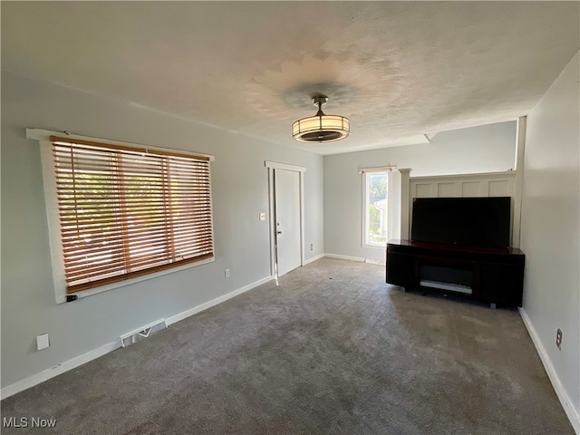 unfurnished living room with dark colored carpet