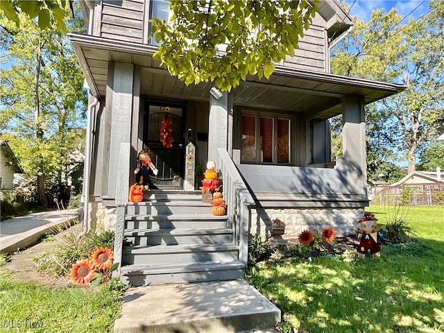 entrance to property with a lawn and a porch