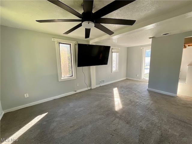 empty room featuring ceiling fan, a textured ceiling, and dark colored carpet