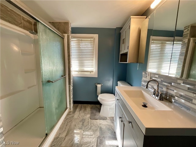 bathroom featuring toilet, decorative backsplash, a shower with shower door, and vanity