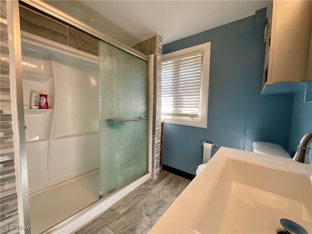 bathroom featuring toilet, a shower with shower door, and vanity