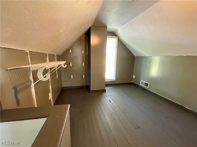 bonus room with dark hardwood / wood-style floors, a textured ceiling, and vaulted ceiling