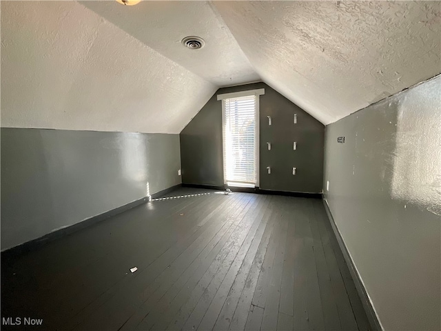 bonus room with hardwood / wood-style flooring, a textured ceiling, and vaulted ceiling