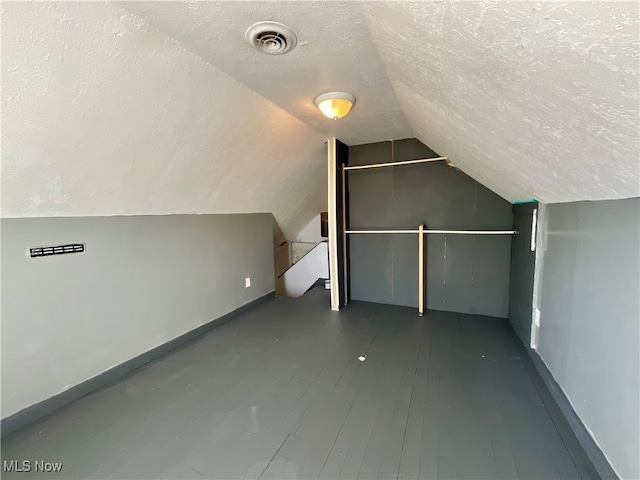 additional living space with a textured ceiling, lofted ceiling, and dark hardwood / wood-style floors