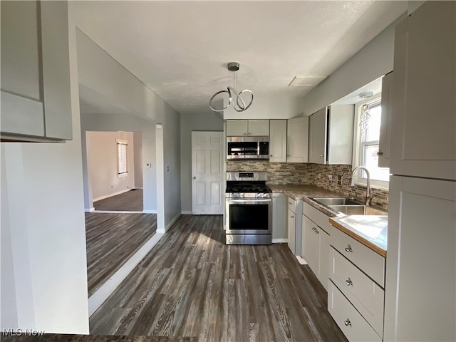 kitchen featuring dark hardwood / wood-style floors, appliances with stainless steel finishes, sink, and decorative light fixtures