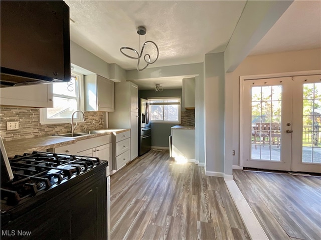 kitchen with sink, white cabinetry, hanging light fixtures, and plenty of natural light