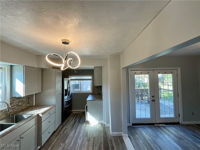 kitchen featuring decorative backsplash, french doors, dark wood-type flooring, hanging light fixtures, and sink