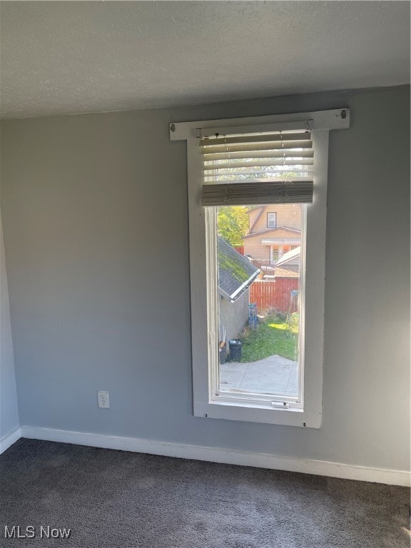 unfurnished room with a textured ceiling and dark carpet