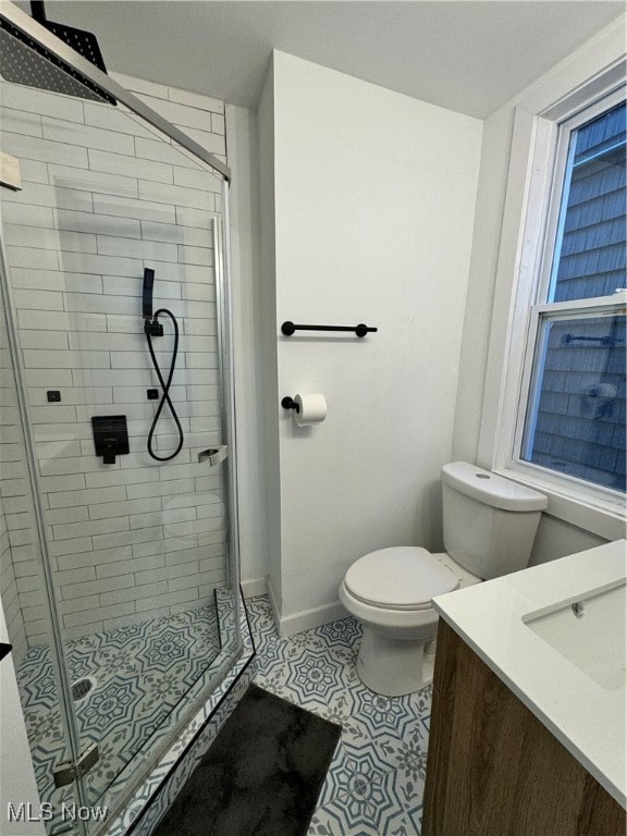 bathroom with tile patterned floors, a shower with shower door, vanity, and toilet