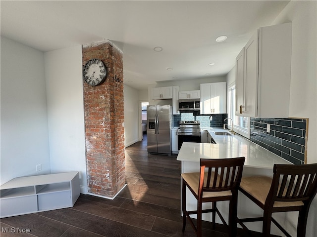 kitchen featuring sink, tasteful backsplash, dark wood-type flooring, white cabinetry, and stainless steel appliances