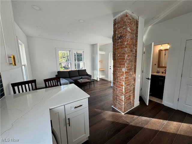 kitchen featuring white cabinets, light stone countertops, dark hardwood / wood-style floors, and ornate columns