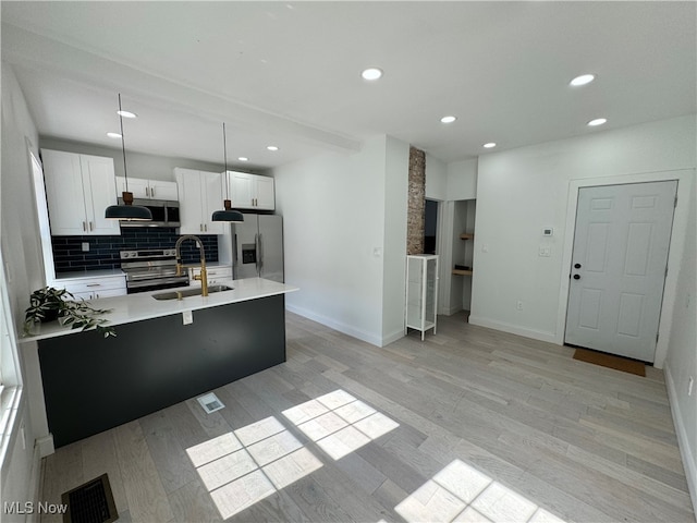 kitchen with pendant lighting, sink, white cabinetry, light hardwood / wood-style flooring, and appliances with stainless steel finishes