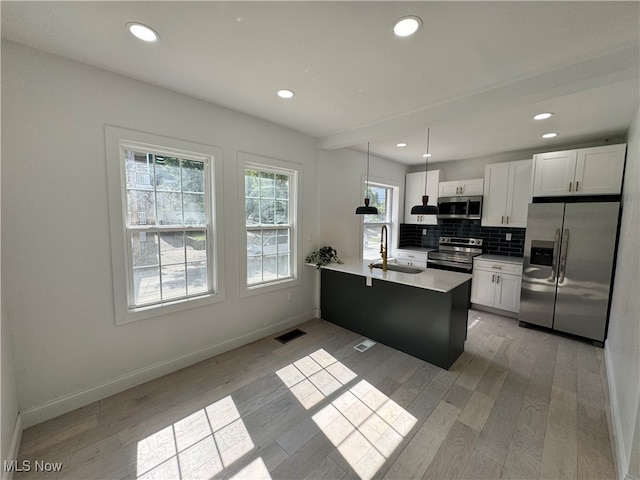 kitchen featuring white cabinetry, pendant lighting, stainless steel appliances, light hardwood / wood-style flooring, and sink