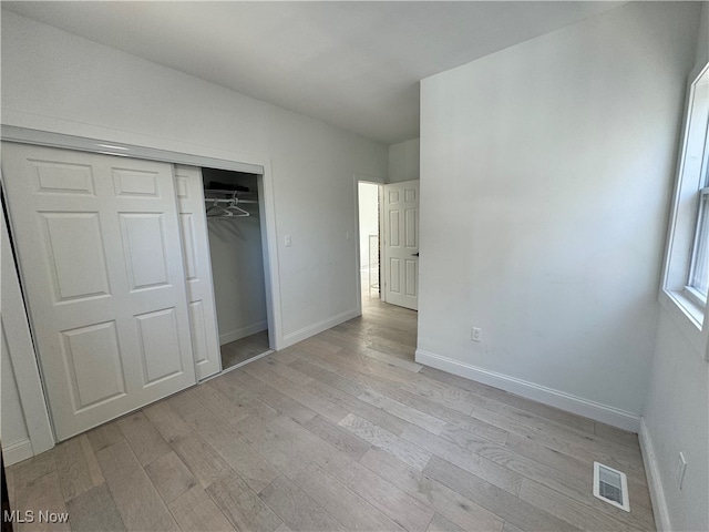 unfurnished bedroom with light hardwood / wood-style flooring and a closet