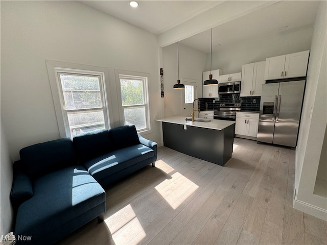 kitchen featuring appliances with stainless steel finishes, hanging light fixtures, white cabinetry, light wood-type flooring, and sink