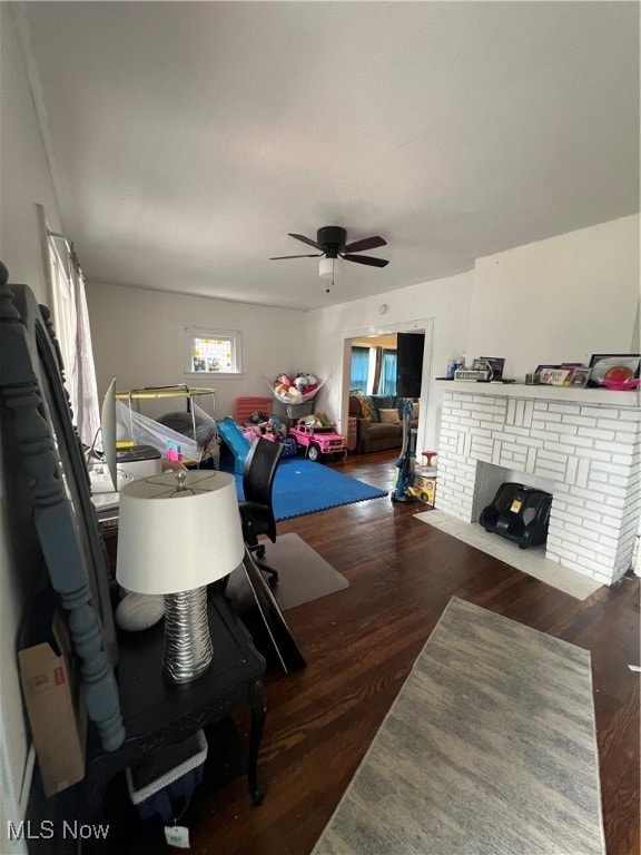 interior space with a brick fireplace, dark hardwood / wood-style floors, and ceiling fan