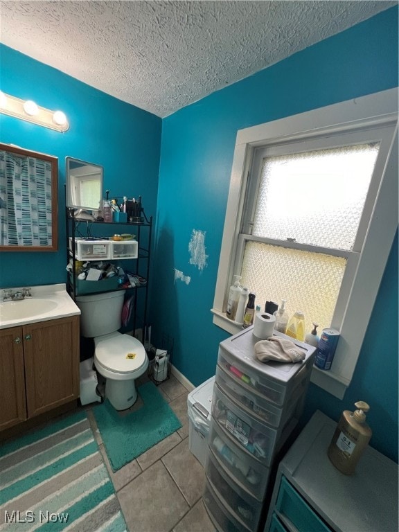 bathroom with tile patterned floors, vanity, toilet, and a textured ceiling