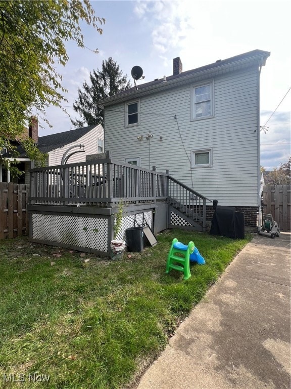 rear view of property featuring a wooden deck and a yard