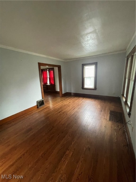 spare room with ornamental molding and dark hardwood / wood-style floors