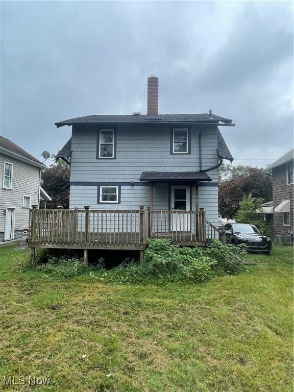 rear view of house featuring a wooden deck and a yard