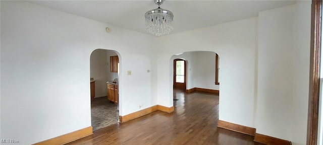 unfurnished room featuring an inviting chandelier and dark hardwood / wood-style floors